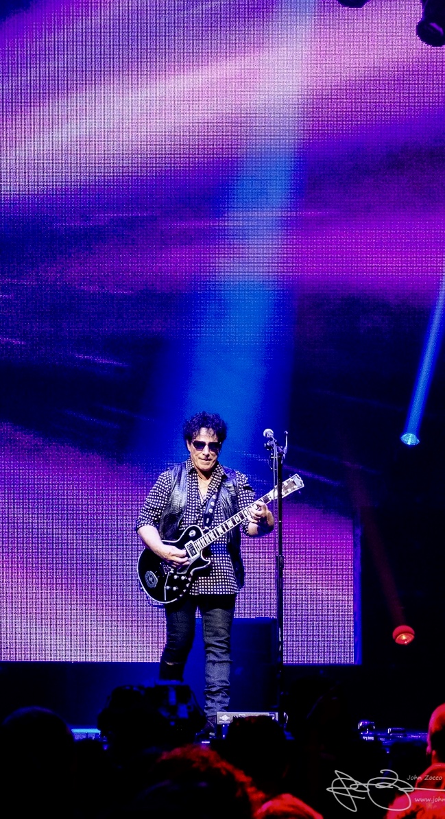 Neal Schon Playing Black Gibson Guitar with a purple backdrop