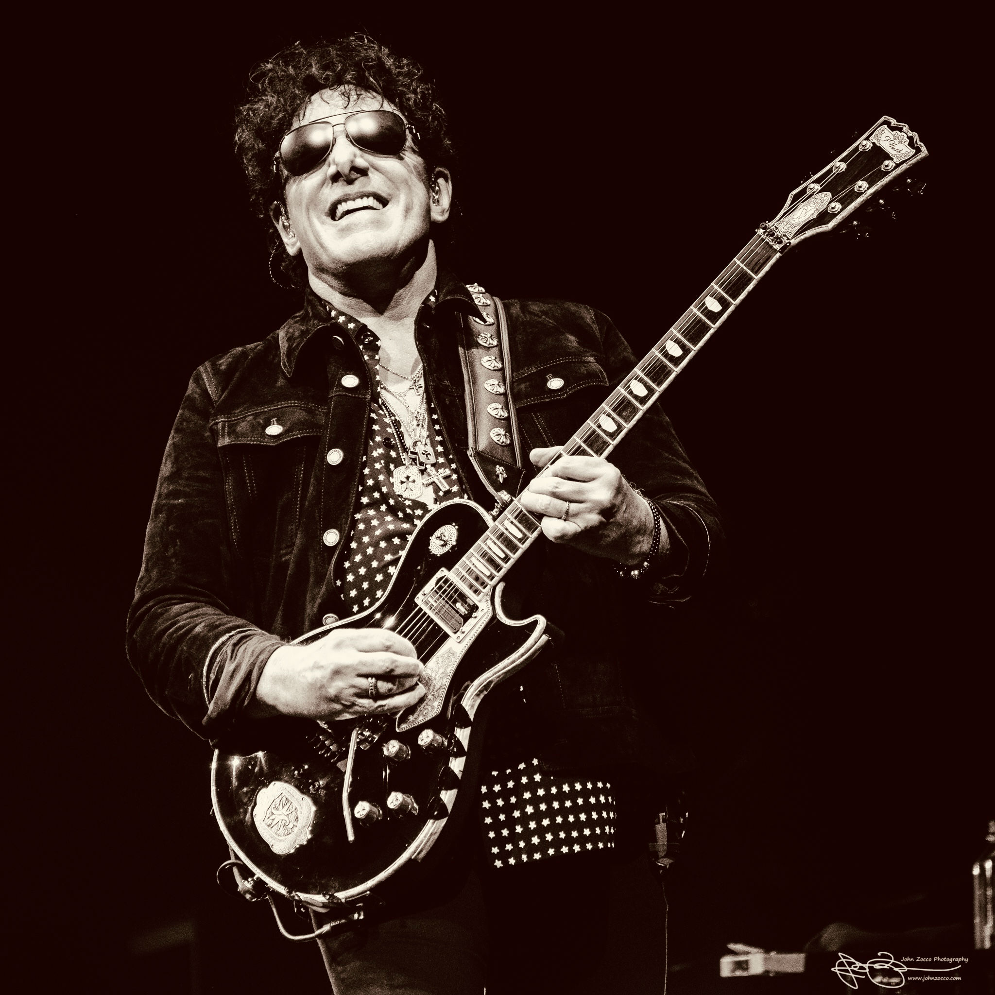 Neal Schon Man in Black Plays Guitar with a Dark backdrop